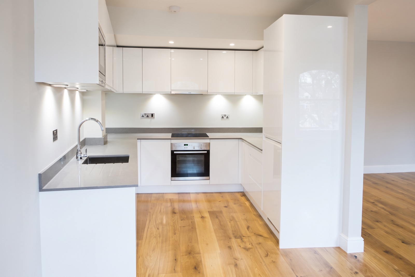 New white gloss kitchen with grey worktops and oak floor